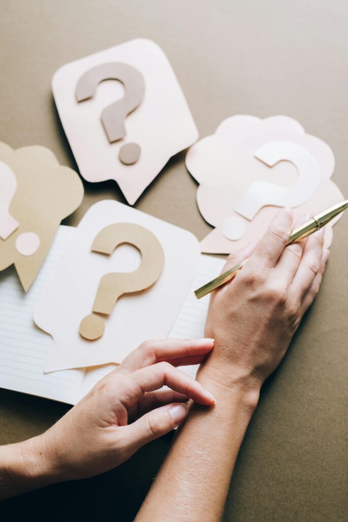 pexels-photo-5428825-5428825 Photo of paper question marks with hands and a pen suggesting curiosity and inquiry.