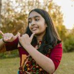 A young girl performs a traditional Indian dance outdoors at sunset, showcasing cultural attire and expressions.